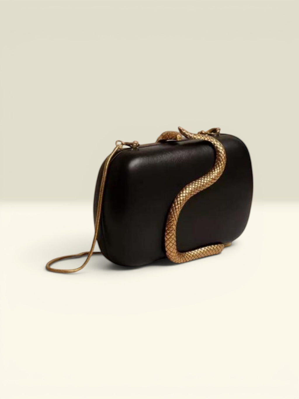 THE GOOD FIND black clutch with gold-tone snake embellishment and chain strap.