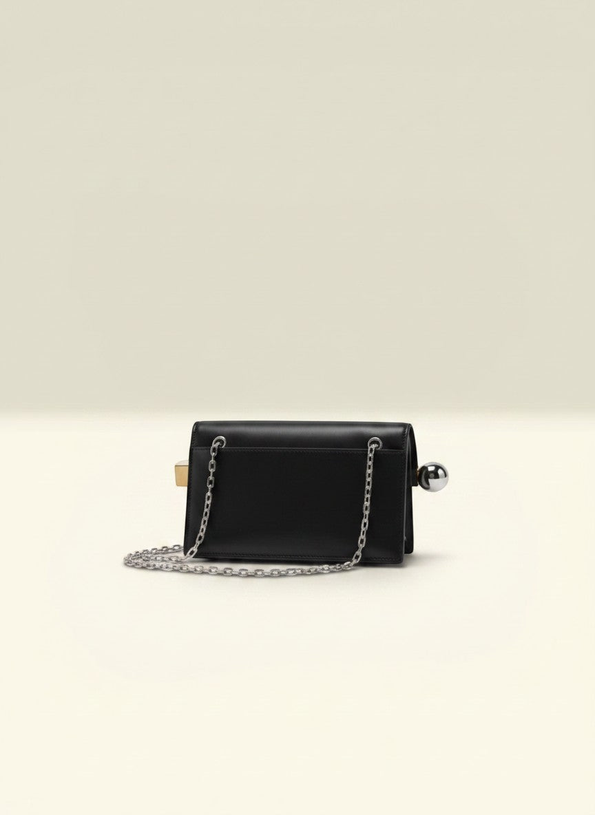 THE GOOD FIND black leather clutch with silver-tone chain strap and unique metallic clasp. Perfect for evening wear.