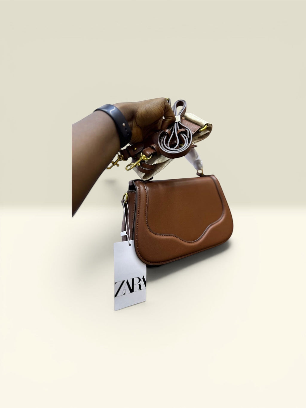 THE GOOD FIND sculpted top handle bag in cognac faux leather with a sculpted flap and gold hardware. Includes detachable strap.