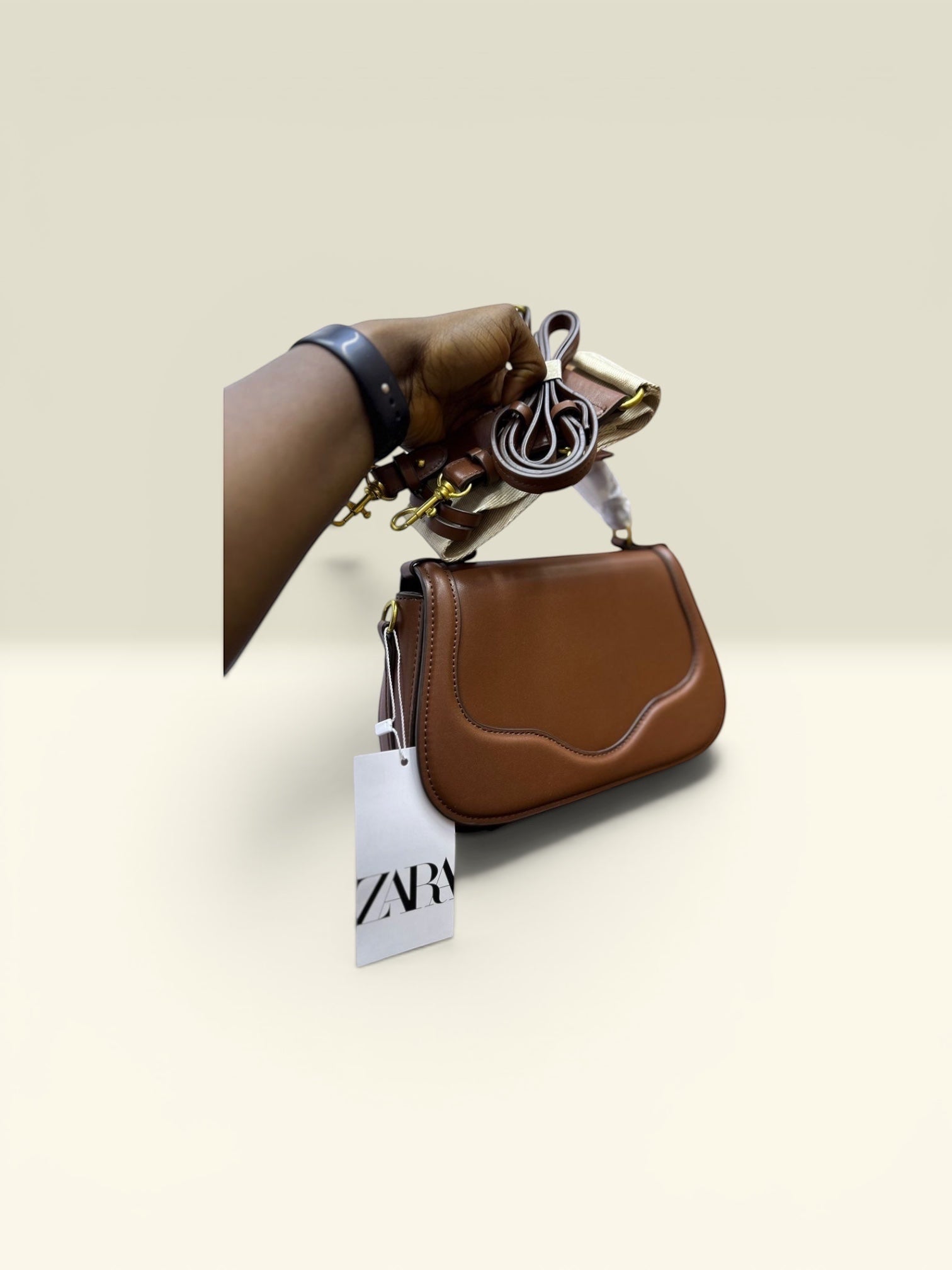 THE GOOD FIND sculpted top handle bag in cognac faux leather with a sculpted flap and gold hardware. Includes detachable strap.