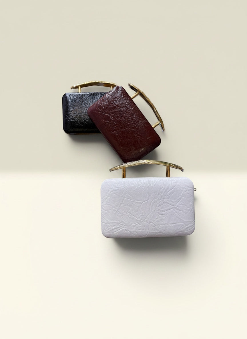 THE GOOD FIND black, burgundy, and white leather clutch purses with gold handles. Textured finish.