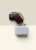 THE GOOD FIND black, burgundy, and white leather clutch purses with gold handles. Textured finish.
