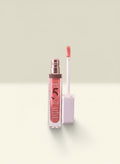 THE GOOD FIND Power Full Liquid Lip Balm in a sheer coral shade, featuring a clear tube with rose gold accents and a doe-foot applicator.