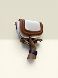 THE GOOD FIND cream and brown faux leather saddle crossbody bag with adjustable strap and gold hardware.