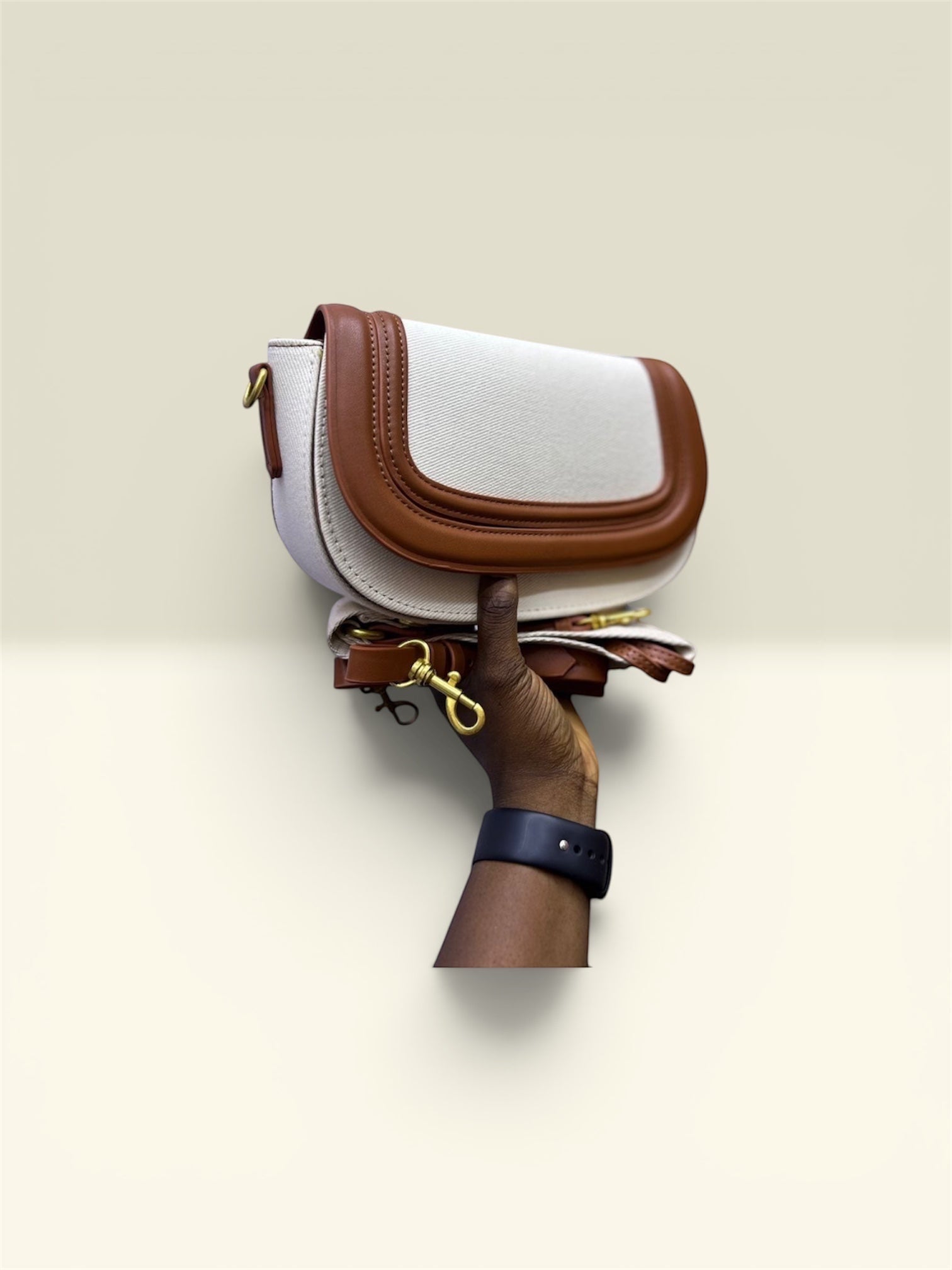 THE GOOD FIND cream and brown faux leather saddle crossbody bag with adjustable strap and gold hardware.